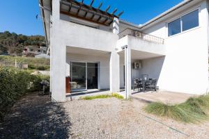 Cette maison blanche dispose d'une terrasse et d'une table. dans l'établissement Residence Cismonte, à Morosaglia
