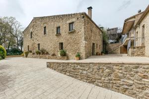 ein altes Steingebäude mit einer Steinmauer in der Unterkunft Habitacions Mas Fuselles in Girona