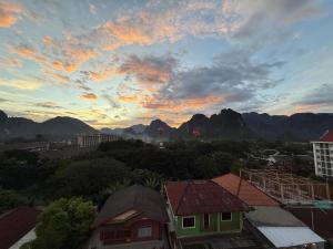 einen Sonnenuntergang über einer Stadt mit Bergen im Hintergrund in der Unterkunft The Rock House Hostel in Vang Vieng