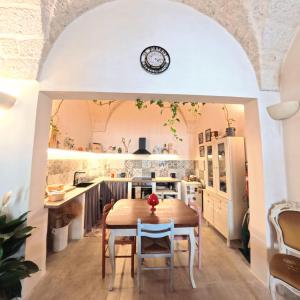 a kitchen and dining room with a table and a clock on the wall at Al Palazzotto in Fasano