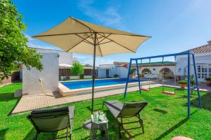 Un patio con dos sillas y una sombrilla junto a una piscina. en Casa rural Entre Olivos, en La Puebla de Cazalla
