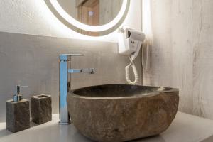 a bathroom with a large stone sink and a mirror at Kleris Apartment 11 Tinos in Agios Sostis +16 photos
