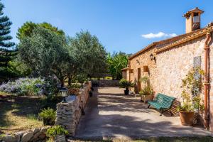 a stone building with a green bench in a garden at Finca Galardo in Son Servera
