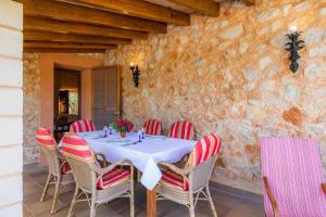 a table with red and white chairs and a stone wall at Finca Galardo in Son Servera