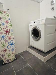 a washing machine in a bathroom with a shower curtain at Minas Ferienwohnung in Dormagen