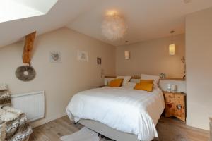 a bedroom with a bed with white sheets and orange pillows at Maison village proche lac d'annecy in Faverges