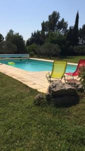 2 sillas de jardín sentadas junto a una piscina en Chinchon, en LʼIsle-sur-la-Sorgue