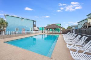 una piscina con sillas blancas y una valla en Feelin' Tip-Sea, en Mustang Beach