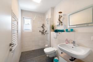 a white bathroom with a toilet and a sink at Lieblingsinsel in Graal-Müritz +23 photos