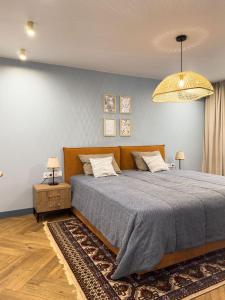 a bedroom with a large bed and a chandelier at Апарт-отель ЗОЛОТОЙ КВАДРАТ premium in Almaty