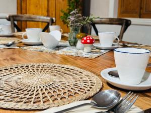 una mesa de madera cubierta con platos, tazas y cucharas en The Beacons Guest House, en Brecon 9 fotos más