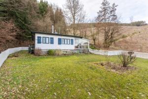 a white house with blue windows in a yard at Homertstuebchen in Eslohe