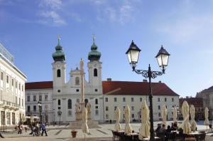 duży biały budynek z dwoma wieżami i światłem ulicznym w obiekcie Duett - Urban Rooms w Győr