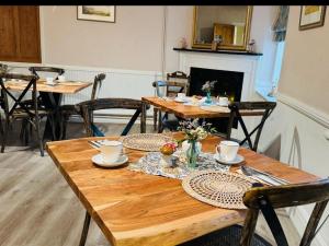 comedor con mesas y sillas de madera y chimenea en The Beacons Guest House, en Brecon