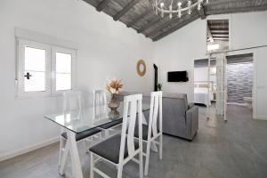 ein Esszimmer mit einem Glastisch und einem Sofa in der Unterkunft Ferro Piscina Climatizada in Chiclana de la Frontera