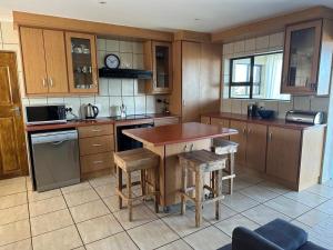 a kitchen with wooden cabinets and a table and stools at SEE n BERG RUSPLEK in Tergniet