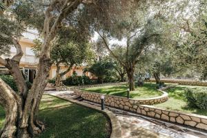 a garden with trees and a stone wall at Resort Trcol in Novalja