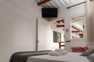 une chambre avec deux lits et une télévision au mur dans l'établissement Pousada Uchimura, à Itapecerica da Serra