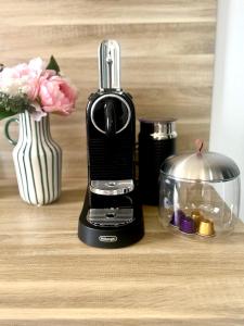 a blender sitting on a table with a vase with flowers at Wörthersee-Appartements in Velden am Wörthersee
