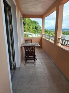 a balcony with a table and a bench on it at Appartement confortable à Saint-Joseph avec piscine in Long-Bois +3 photos