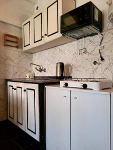 a kitchen with white cabinets and a microwave at Zurita Apart in San Fernando del Valle de Catamarca