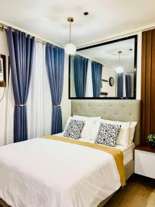 a bedroom with a large bed with blue curtains at Cozy Belle Suite Relaxing Place at SMDC Hope Residences in Trece Martires
