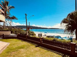 a fence in front of a beach with the ocean at Experiência única em Bombinhas frente ao Mar. in Bombinhas