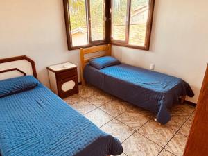 a bedroom with two beds and two windows at Experiência única em Bombinhas frente ao Mar. in Bombinhas