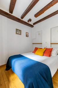 une chambre avec un grand lit blanc avec des oreillers colorés dans l'établissement Charmant et typique 2 pièces Place de la Cathédrale, à Strasbourg