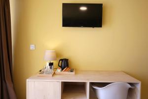 a desk with a television on a yellow wall at Kai Boutique Studio & Rooms in Zadar
