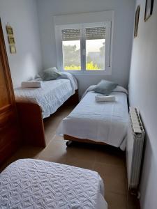 two beds in a room with two windows at Casa El Cerezo Rojo in El Rasillo