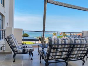 uma varanda com um sofá e cadeiras e vista para o oceano em Santos 24 em Mossel Bay