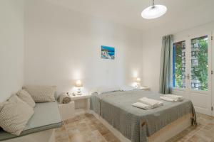 a white bedroom with a bed and a window at Maria's Village Villa Anemomylos in Aliki