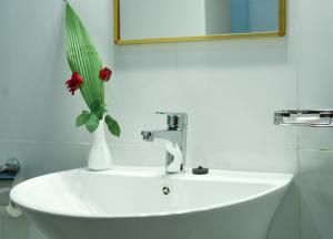 a white sink with a vase with red flowers in it at Ridar Hotel in Seeta