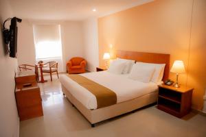 a hotel room with a bed and a table and a chair at GIO Hotel Vajamar Valledupar in Valledupar