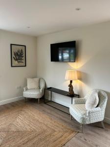 a living room with two chairs and a tv on the wall at Newditch Farm - BRS Airport in Bristol