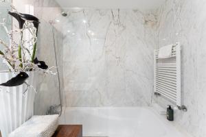 a bathroom with a white tub and a white marble wall at GuestReady - Moledo's beach and sun in Santana