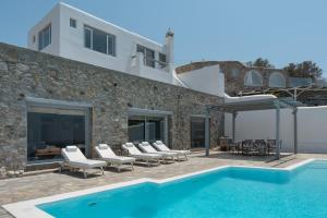 a villa with a swimming pool and lounge chairs at Villa Coventina - Family Residence in Agios Ioannis Mykonos