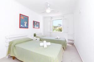 a white room with two beds and a window at Casa Joana Cap d'Artrutx in Cala'n Bosch