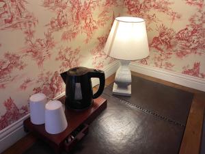 a lamp and a coffee pot on a table with towels at BRIT HOTEL & SPA Le Roc au Chien in Bagnoles de l'Orne