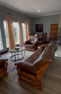 a living room with a leather couch and a table at Madeley House Unit 2 near Oliver Tambo Airport in Boksburg