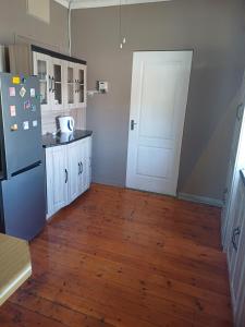 een keuken met een koelkast en een houten vloer bij Serene on 5 Cologne in Germiston