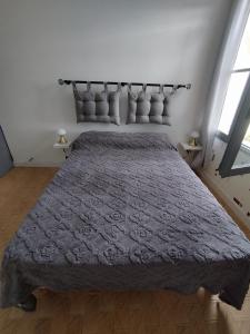 une chambre avec un grand lit recouvert d'une couverture grise dans l'établissement Chez Monique et Dédé, à Ferrassières