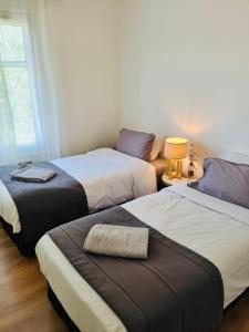 drie bedden in een slaapkamer met een lamp op een tafel bij Villa Mel's in Bannay