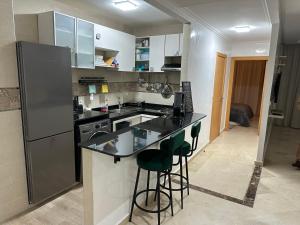 a kitchen with a refrigerator and a counter with stools at Appartement Haut standing in Mohammedia