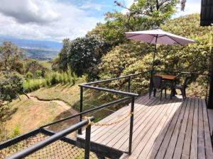 una terrazza in legno con tavolo e ombrellone di Luna Creciente Refugio de Luz y Naturaleza a Silvania Altre 10 foto