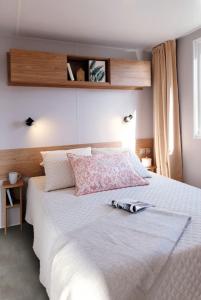 - une chambre avec un lit blanc et une bouteille dans l'établissement FMLODGE- sables du midi mobilhome les glycines, à Valras-Plage