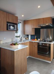 - une cuisine avec des placards en bois et un bol de fruits sur le comptoir dans l'établissement FMLODGE- sables du midi mobilhome les glycines, à Valras-Plage 1 autre photo