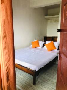 a bed with orange and white pillows on it at Ameeila Villa in Kandy