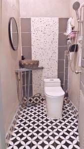 a bathroom with a toilet and a black and white tile floor at Dokchampa River View Villa in Nongkhiaw